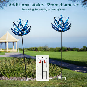 Blue wind spinner with additional stake on grassy area with gazebo in the background