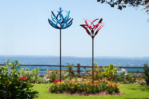 In a beautiful garden, two metal wind spinners decor the landscaping more fascinating.